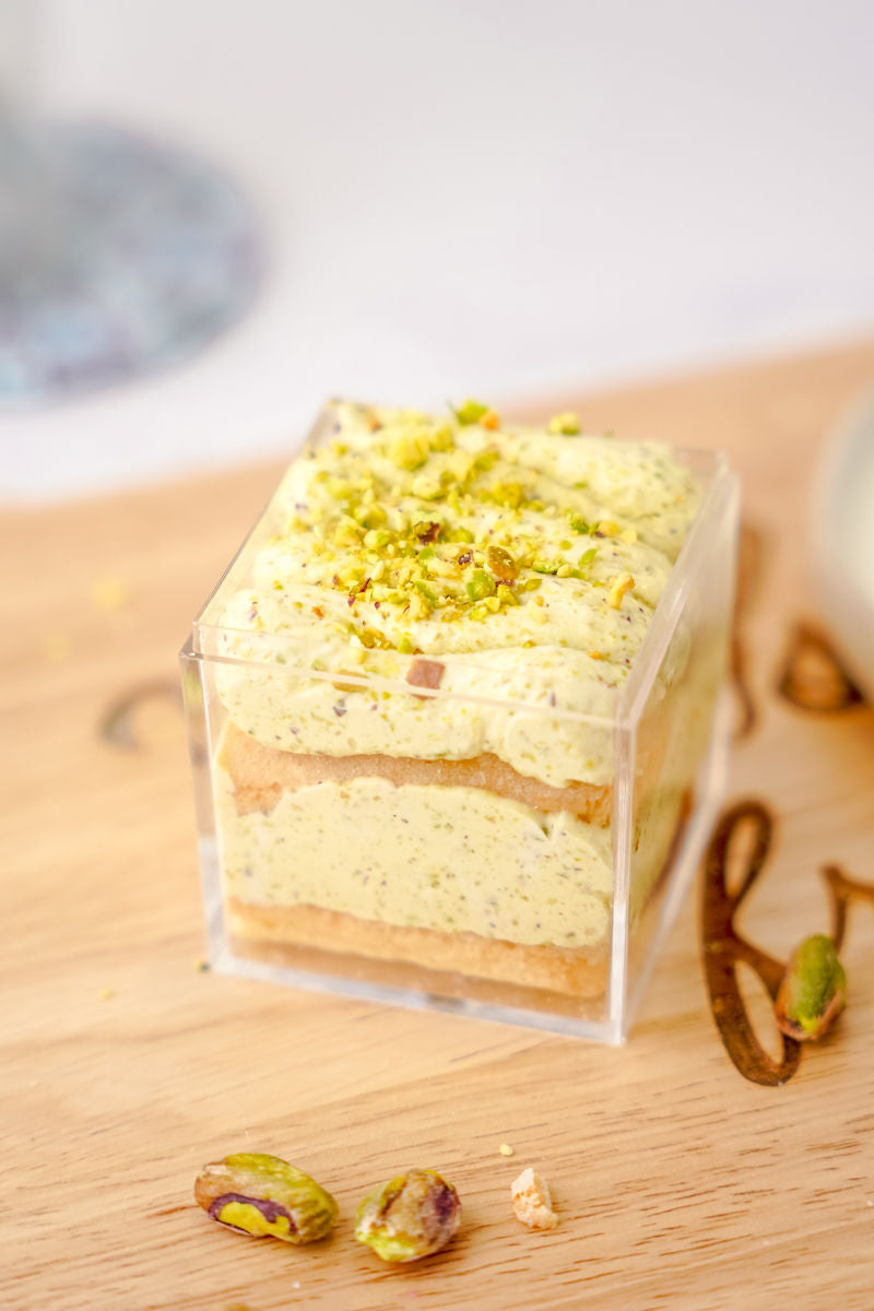 Grain-free mini pistachio tiramisu on a wooden cutting board.