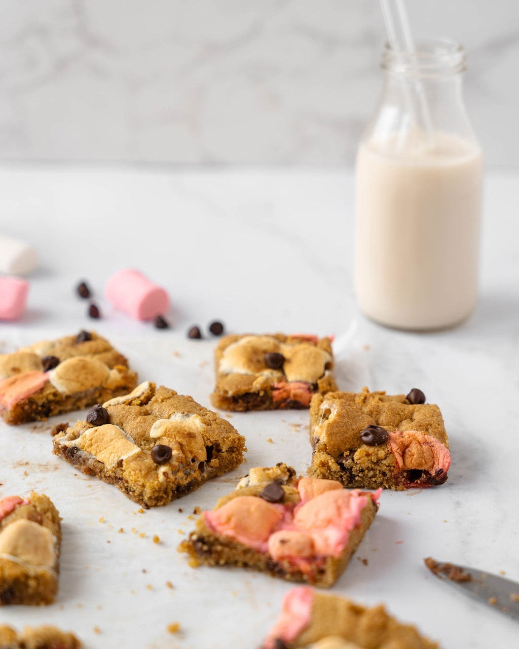 Grain-Free S'mores bars with multicolored marshmallows. Bottle of milk with straw in background