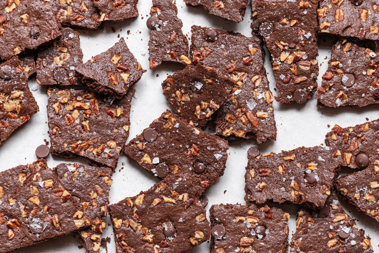 brownie brittle shards topped with salt, chocolate, and chopped nuts. shards are scattered on countertop