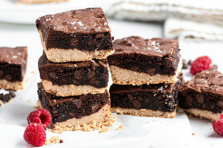 2 stacks of grain-free shortbread brownies with sea salt on top, with raspberries on counter
