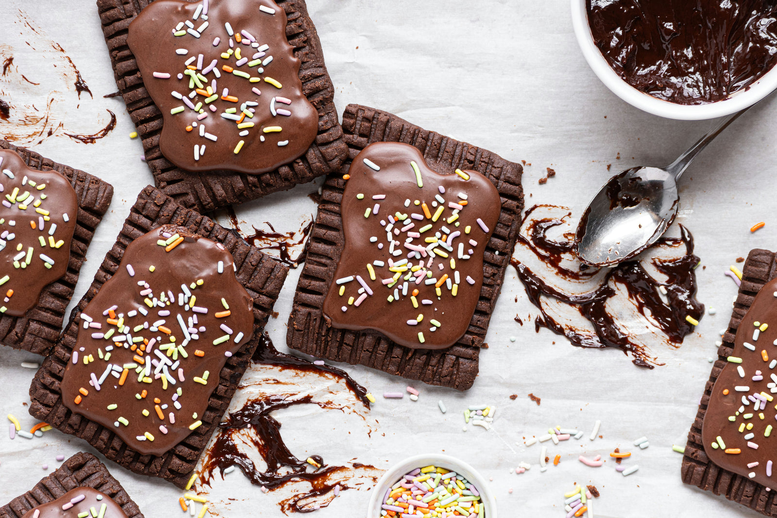 Several chocolate fudge pop-tarts with chocolate frosting and sprinkles on a counter